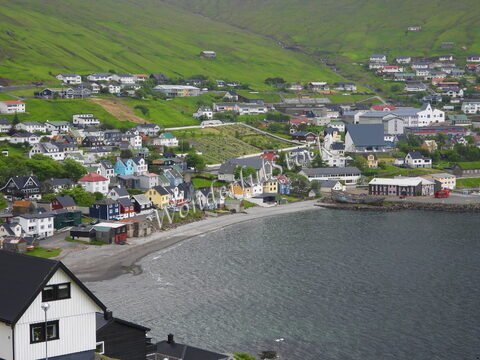 Fuglafjørður, Îles Féroé, avec des maisons colorées sur la pente verdoyante et une plage au bord de l'eau.