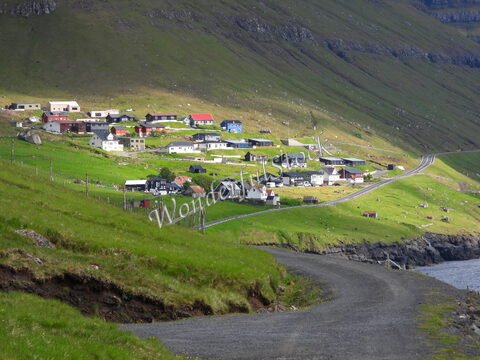 Village de Kunoy aux îles Féroé, avec des maisons colorées et une route sinueuse longeant la côte.