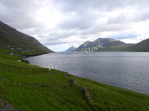 Vue sur le fjord avec des collines verdoyantes et des maisons à Kunoy, Îles Féroé.