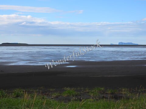 Plage de sable noir avec des îlots au loin, Islande.