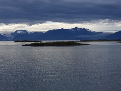 Île dans un lac avec des montagnes en arrière-plan, Islande.