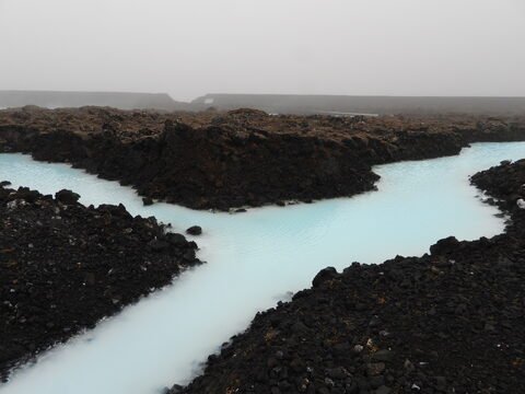 Eau bleu clair entourée de roches noires, Blue Lagoon, Islande.