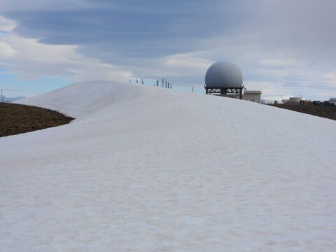Neige sur une colline avec une structure sphérique à Bolafjall, Islande.