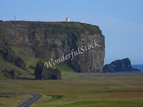 Falaises de Dyrhólaey en Islande, avec un phare et des formations rocheuses sur la côte.