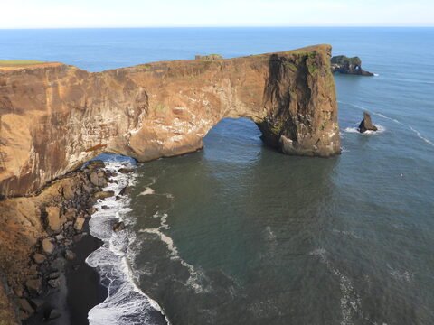 Dyrhólaey en Islande, avec une falaise imposante et une mer agitée au premier plan.