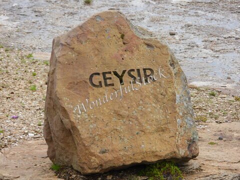 Geysir, Islande, avec une pierre marquée du nom du geyser sur un sol rocheux et légèrement humide.