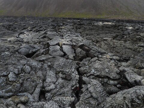 Surface de lave noire à Grindavík, Islande, avec des fissures et un relief texturé.