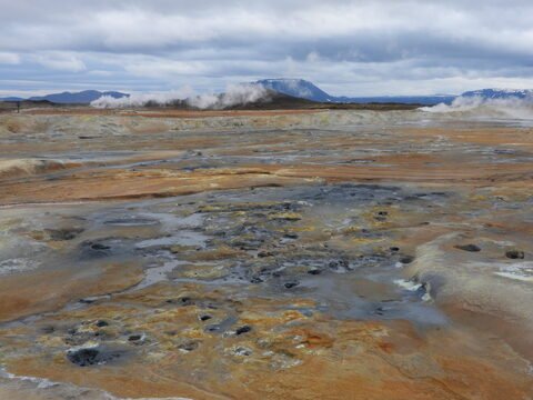Terrains géothermiques avec fumerolles à Hverir, Islande, présentant des couleurs terreuses et des cratères bouillonnants.