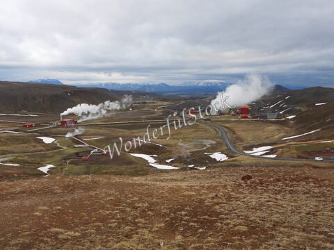 Vapeurs géothermiques et installations industrielles à Hverir, Islande, avec des montagnes en arrière-plan et un paysage désertique.