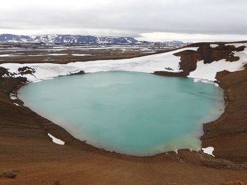 Lac turquoise entouré de terres volcaniques et de neige, situé à Krafla, Islande.