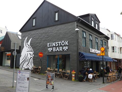 Bar Einstök à Reykjavík, Islande, avec une façade grise et des tables extérieures, entouré de bâtiments colorés.