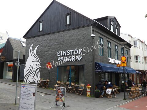 Bar Einstök à Reykjavík, Islande, avec une façade grise et des tables extérieures, entouré de bâtiments colorés.