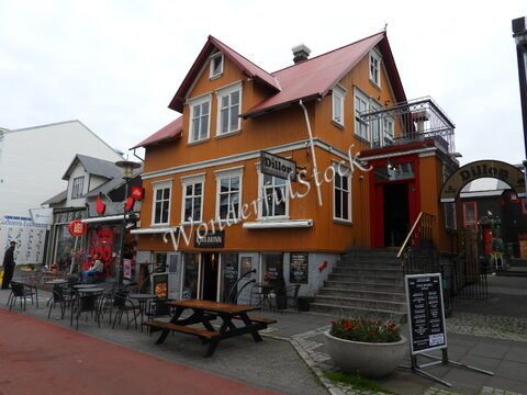 Bâtiment coloré avec des tables à l'extérieur, situé à Reykjavík, Islande. Le restaurant Dillon est visible avec son enseigne distinctive.