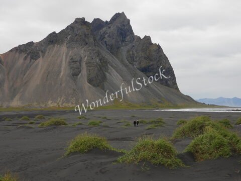 Vaste étendue de sable noir avec des herbes, dominée par la montagne Vesturhorn, en Islande.