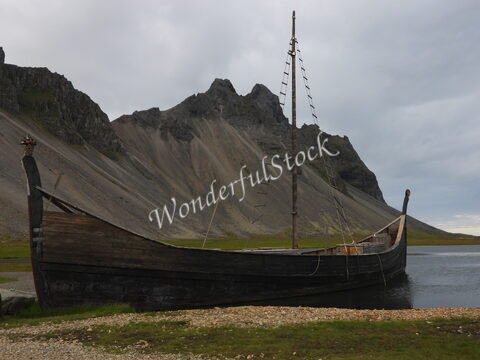 Un bateau en bois est amarré près des montagnes à Vesturhorn, en Islande.