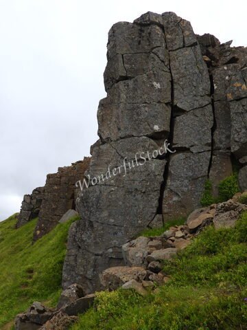 Falaises de Gerðuberg en Islande, avec des formations rocheuses verticales et une végétation verdoyante au pied.