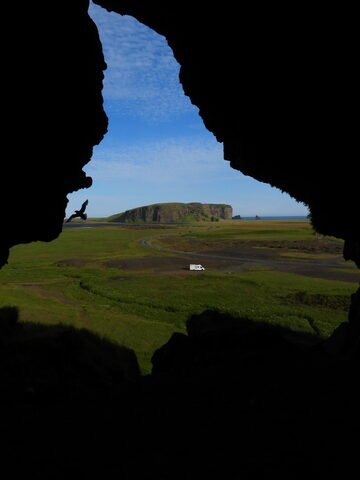 Caverne de Loftsalahellir en Islande, avec un véhicule blanc et des paysages verdoyants en arrière-plan.