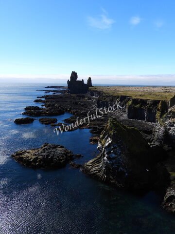Londrangar en Islande, formations rocheuses sur une côte avec mer calme et ciel dégagé.