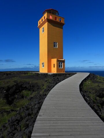 Phare orange sur un chemin en bois, Öndverðarnes, Islande.