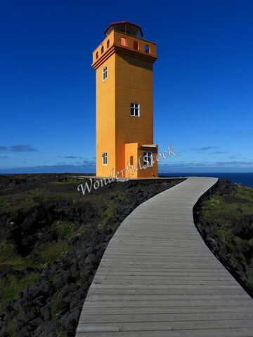 Phare orange sur un chemin en bois, Öndverðarnes, Islande.