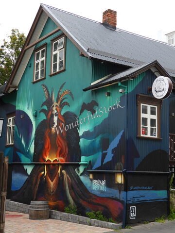 Fresque représentant une figure mythologique sur un bâtiment à Reykjavík, Islande, avec des couleurs vives et des éléments de paysage.