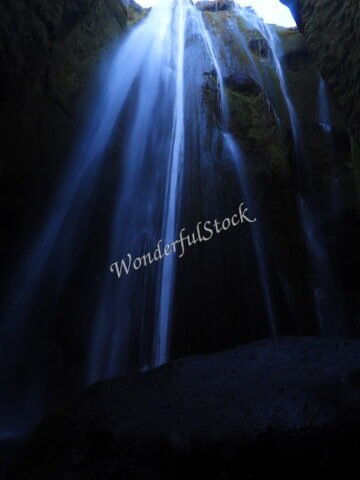 Cascade de Seljalandsfoss en Islande, avec des parois rocheuses et un éclairage sombre.