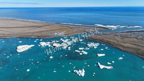 Icebergs flottants sur la plage de diamant en Islande, avec des eaux turquoise et un paysage côtier.