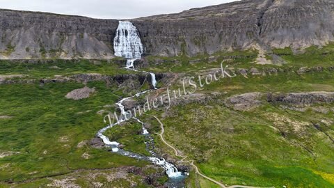 Cascade à Hæstahjallafoss, Islande, entourée de verdure et de formations rocheuses.