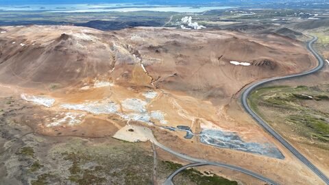 Vue aérienne de Hverir, Islande, montrant des formations géologiques et des zones de sol altéré avec des couleurs variées.
