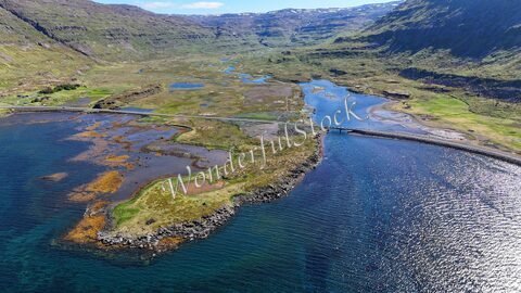 Lambagil, Islande, vue aérienne d'une vallée avec un cours d'eau, des terres humides et des collines verdoyantes en arrière-plan.