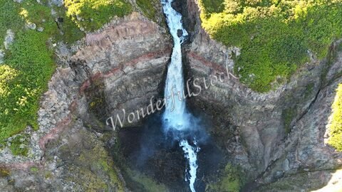 Cascade de Lambagil en Islande, entourée de falaises rocheuses et de végétation verdoyante.