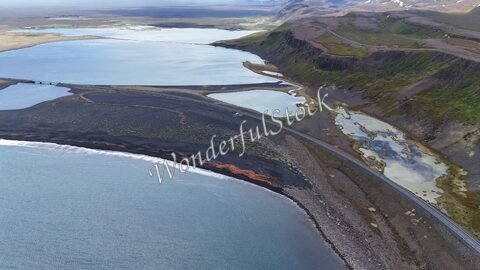Vue aérienne d'Öxarfjörður en Islande, présentant des plages de sable noir et des lacs aux eaux calmes.