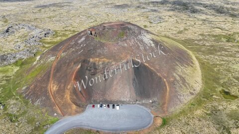 Crater de Saxhóll en Islande, avec des pentes colorées et un parking au pied.