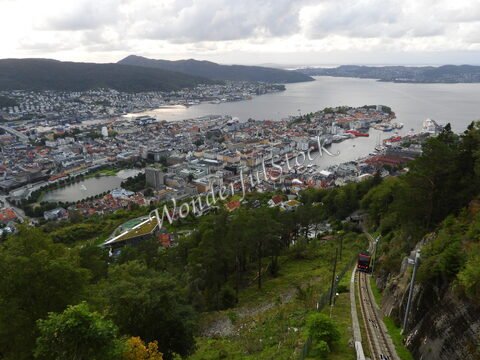 Vue panoramique de Bergen, Norvège, avec des maisons colorées, un port et une ligne de funiculaire descendant la colline.