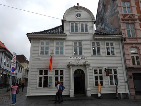 McDonald's situé à Bergen, Norvège, dans un bâtiment blanc au style architectural distinctif, avec des panneaux de signalisation à proximité.