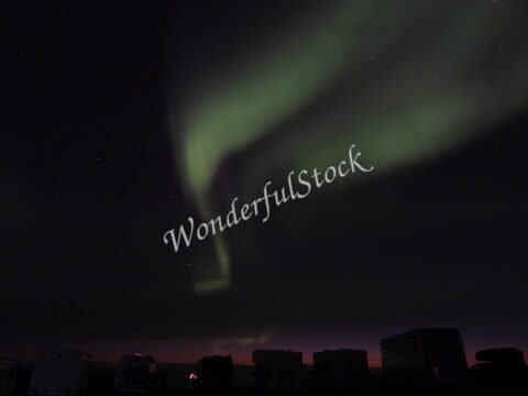 Aurores boréales au Cap Nord, Norvège, illuminant le ciel nocturne, avec des silhouettes de véhicules en premier plan.