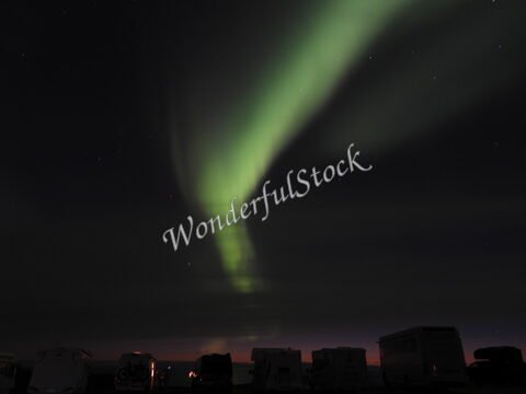 Aurores boréales au Cap Nord, Norvège, avec des camping-cars visibles au premier plan sous un ciel nocturne étoilé.