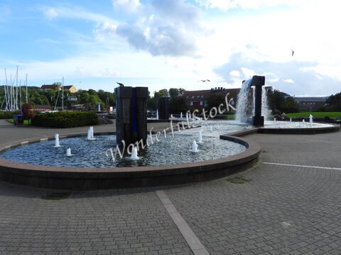 Fontaines dans un parc à Kristiansand, Norvège, avec des jets d'eau et des bâtiments en arrière-plan.