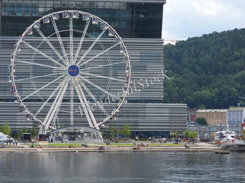 Grande roue près de l'opéra à Oslo, Norvège, avec des visiteurs et des bâtiments colorés en arrière-plan.