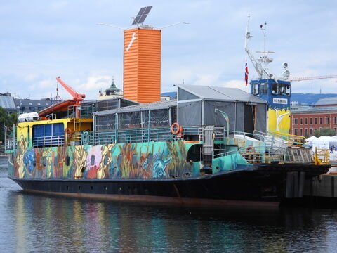 Bateau coloré amarré à Oslo, Norvège, avec des motifs marins sur sa coque et une cabine surélevée.