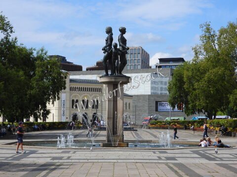 Fontaine avec sculptures d'enfants au centre, entourée de verdure et de bâtiments modernes à Oslo, Norvège.