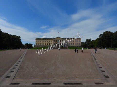 Palais royal à Oslo, Norvège, avec des visiteurs sur l'esplanade et un ciel partiellement nuageux.