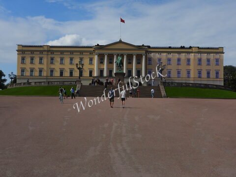 Palais avec statue à Oslo, Norvège, entouré de visiteurs sur une vaste esplanade.