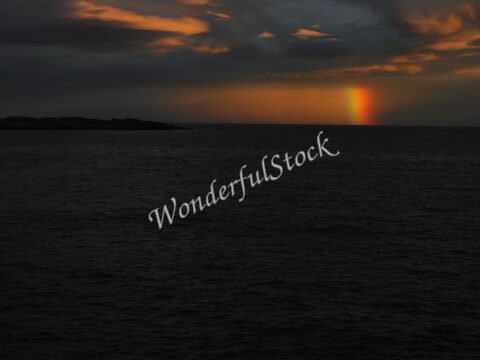 Lumière du soleil se reflétant sur la mer, avec un arc-en-ciel, en Norvège.