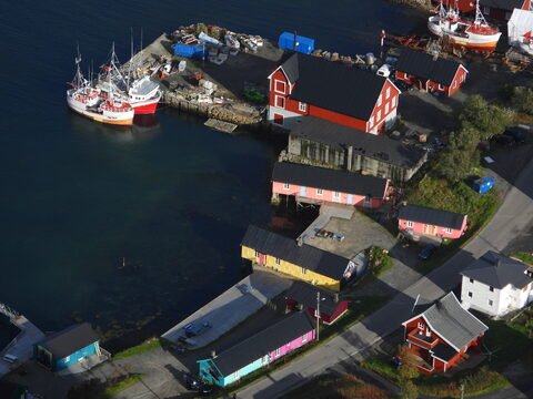 Bateaux de pêche et maisons colorées à Reinebringen, Norvège, au bord de l'eau, avec un quai et des structures en bois.
