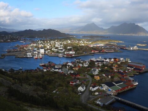 Vue panoramique de maisons colorées au bord de l'eau à Reinebringen, Norvège, avec des montagnes en arrière-plan.