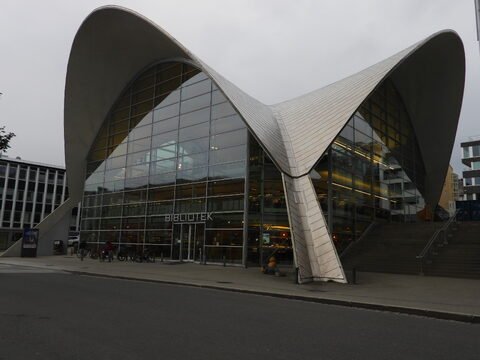 Bibliothèque moderne à Tromsø, Norvège, avec une architecture aux formes courbes et une façade en verre.