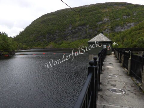 Bâtiment en bois sur un quai au bord d'un lac, entouré de collines verdoyantes en Norvège.
