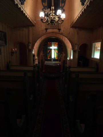 Intérieur de l'église Stavkirke à Savjord, Norvège, avec un vitrail coloré et un lustre en bois.