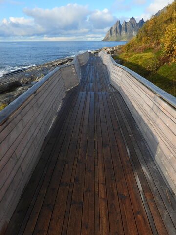 Allée en bois menant à la mer, entourée de montagnes, à Tungeneset, Norvège.